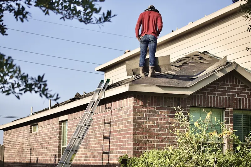 Professional roofer working on a residential roof in Marchand